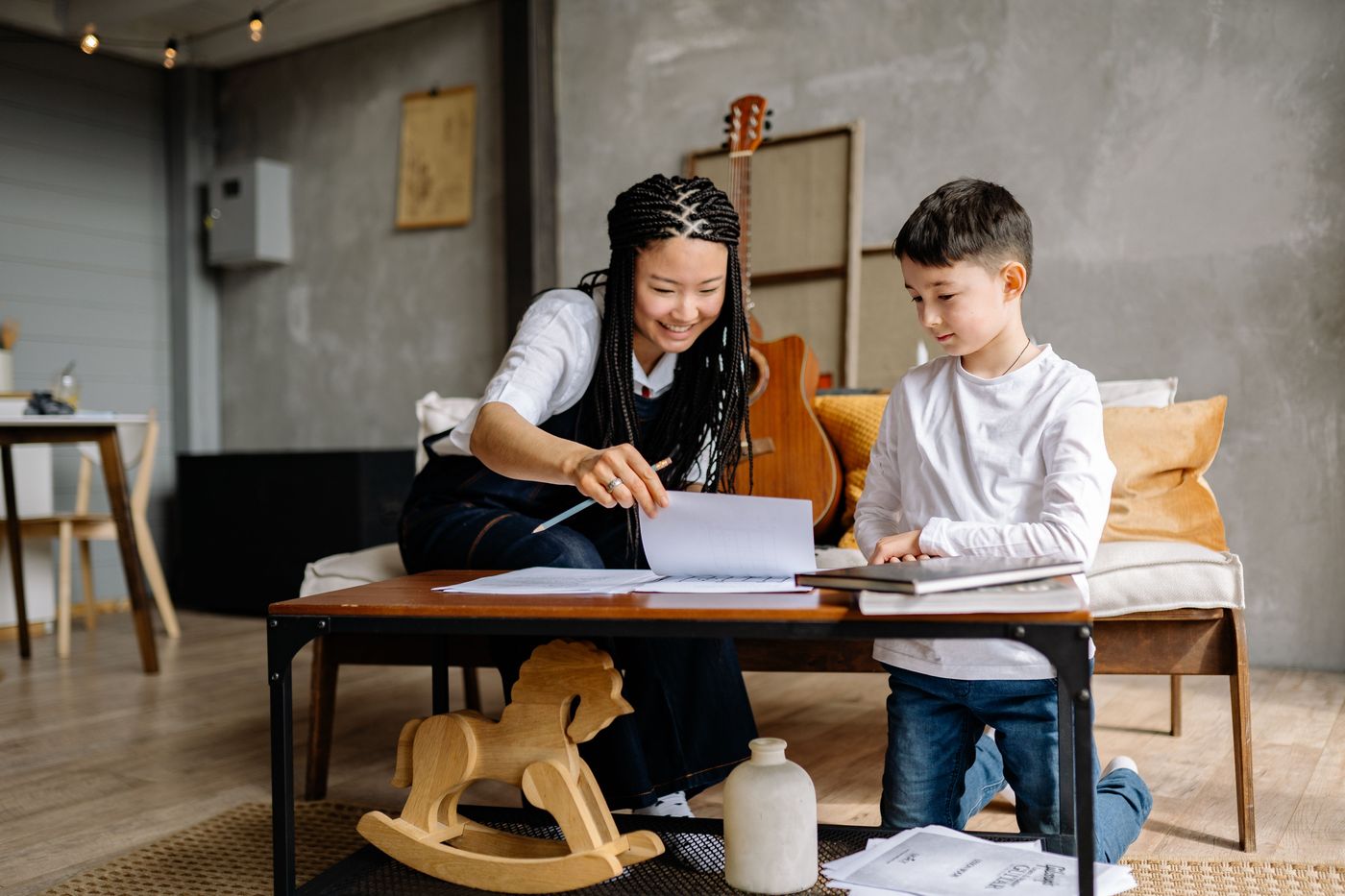 A tutor and a young boy working through reading materials at a coffee table
